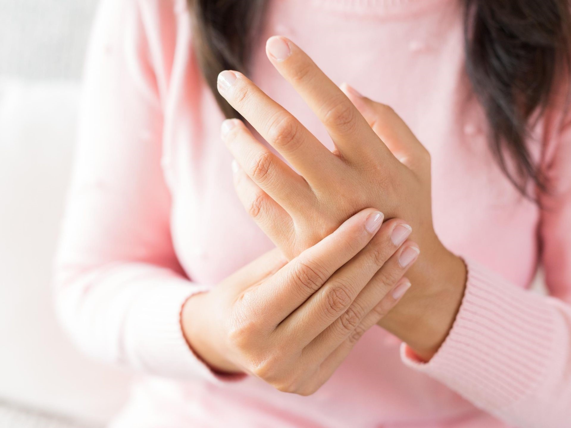 Una ragazza con una maglietta rosa che si tocca la mano
